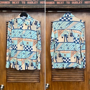 Peut inclure: Une chemise à manches longues avec un motif géométrique bleu, blanc et orange. La chemise présente une image répétée d'un homme jouant de la guitare avec le texte "Johnny Guitar" sur la chemise.