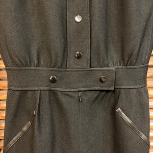 Puede incluir: Un vestido negro con cierre de botones, cintur&oacute;n y dos bolsillos con ribetes de cuero.