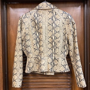 Puede incluir: Una chaqueta de color marr&oacute;n y negro con estampado de piel de serpiente, cintura ajustada y mangas largas.