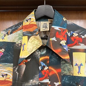 May include: A black button-down shirt with a colorful pattern featuring Mickey Mouse as a sorcerer. The shirt has a large collar and a label that reads "EDMONDSON CALIFORNIA".