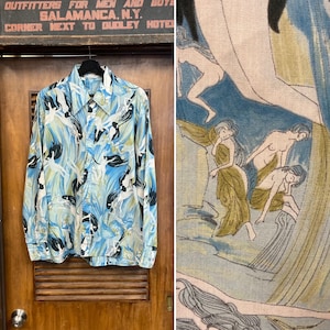 Puede incluir: Una camisa azul de manga larga con un estampado de mujeres en una escena acuática. La camisa tiene un cuello abotonado y un frente abotonado. El estampado es en tonos de azul, verde y blanco.