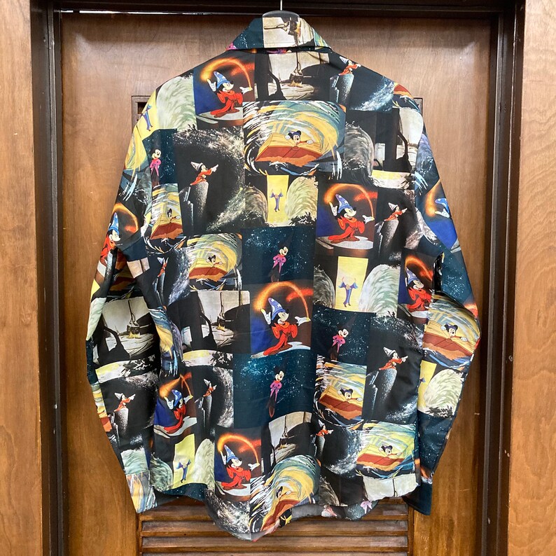 May include: A black long-sleeved button-up shirt with a colorful patchwork design featuring various images of Mickey Mouse as the Sorcerer's Apprentice from the movie Fantasia.