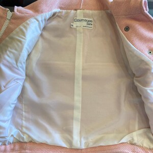 May include: Pink corduroy jacket with a white lining and a Courr&egrave;ges Paris label. The jacket has a zipper closure and button accents.