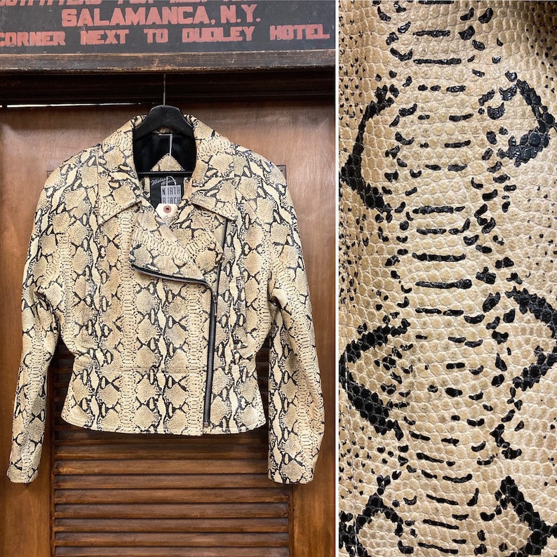 Puede incluir: Una chaqueta de cuero de serpiente beige y negra con cierre de cremallera. La chaqueta tiene una etiqueta de North Beach en el cuello.