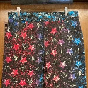 May include: A pair of blue, red, and white star-patterned denim shorts. The stars are printed in a distressed, abstract style.