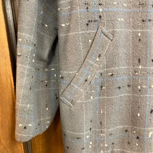 May include: A grey plaid jacket with a blue and white pattern. The jacket has a flap pocket on the left side.