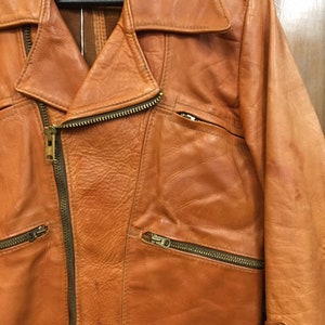May include: A brown leather jacket with a zipper closure and multiple pockets. The jacket has a classic biker style.