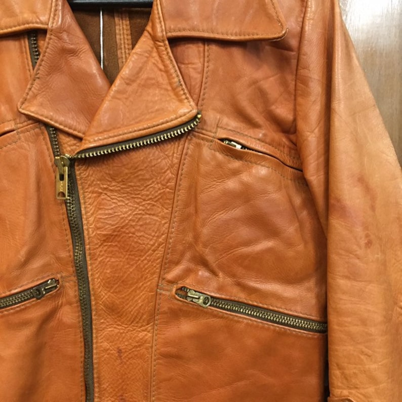 May include: A brown leather jacket with a zipper closure and multiple pockets. The jacket has a classic biker style.