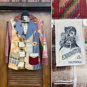 May include: A multi-colored patchwork blazer with a contrasting blue collar and lapels. The blazer has a variety of patterns, including plaid, floral, and geometric designs. The label on the blazer reads "Kennington Ltd. California".