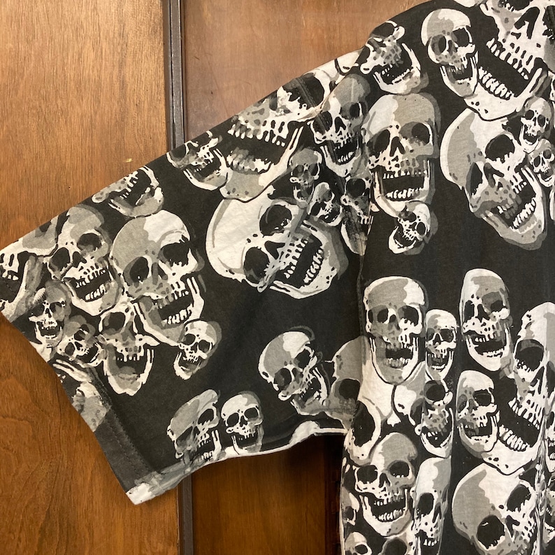Puede incluir: Tela de estampado de calavera en blanco y negro. La tela presenta un patr&oacute;n repetitivo de calaveras con diferentes expresiones.