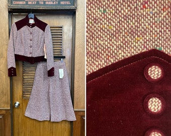 May include: A two-piece suit in a pink and brown tweed fabric with a burgundy velvet trim. The jacket has a collar, buttons, and pockets. The skirt is a-line and has a high waist. The suit is hanging on a wooden door with a sign that reads "New York Clothing Store".
