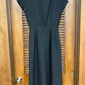 Puede incluir: Un vestido midi negro con mangas cortas y escote en V. El vestido tiene un corpi&ntilde;o ajustado y una falda fluida.