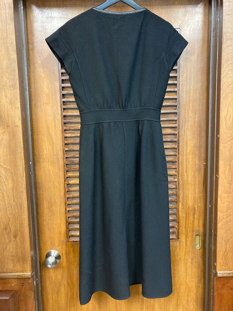 Puede incluir: Un vestido midi negro con mangas cortas y escote en V. El vestido tiene un corpi&ntilde;o ajustado y una falda fluida.