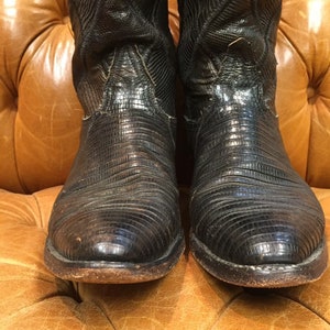 Pu&ograve; includere: Un paio di stivali da cowboy in pelle nera con un motivo testurizzato a pelle di serpente.
