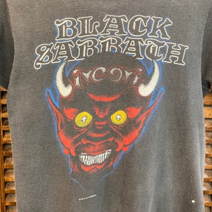 May include: Black Sabbath vintage t-shirt with a red devil head graphic and the band's name in a stylized font.