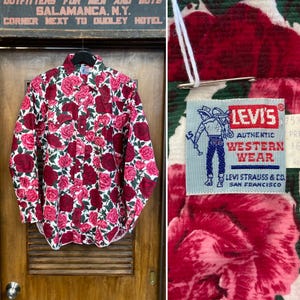 May include: A white long-sleeved shirt with a red and pink rose print. The shirt has a button-down collar and a Levi's Authentic Western Wear label.