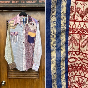 May include: A patchwork long-sleeve shirt with a variety of floral and geometric patterns in shades of blue, red, white, and yellow. The shirt has a button-down collar and a single chest pocket.