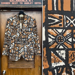 Puede incluir: Una chaqueta de traje marrón, negra y blanca con un diseño geométrico. La chaqueta tiene cierre de botón y solapa de muesca. La tela tiene una textura tejida.