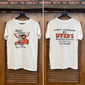 Puede incluir: Camiseta blanca con un gráfico de hot rod rojo y el texto "Street Charger by Dyer's Machine" en la parte delantera. La parte trasera de la camiseta muestra "Street Chargers by Dyer's Machine Service, Summit, ILL. 312-496-8100".