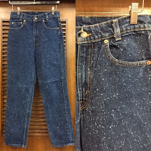 May include: A pair of blue denim jeans with a white speckled pattern. The jeans have a high waist and a straight leg.