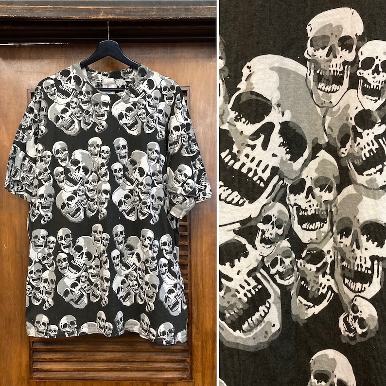 Puede incluir: Camiseta negra con un patr&oacute;n de calaveras blancas. Las calaveras est&aacute;n dispuestas en un patr&oacute;n aleatorio y son de diferentes tama&ntilde;os.