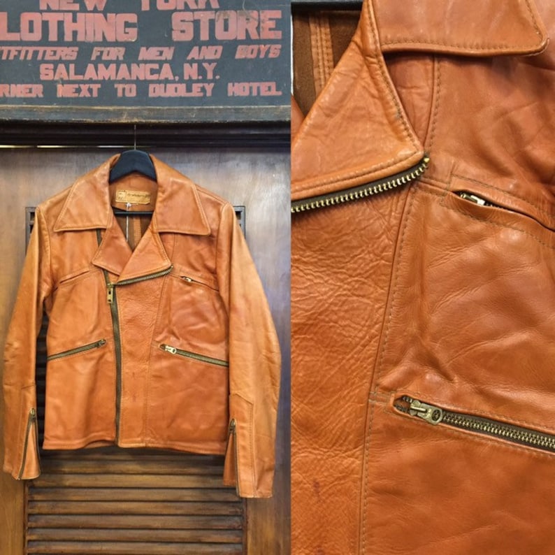 May include: A brown leather jacket with a zipper closure and multiple pockets. The jacket has a collar and long sleeves. The jacket is hanging on a hanger.