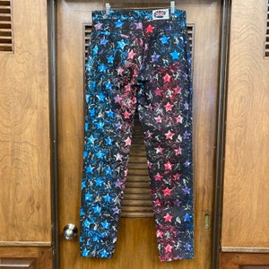 May include: A pair of blue and red jeans with a star pattern. The jeans have a faded look and are made of a soft, comfortable material.
