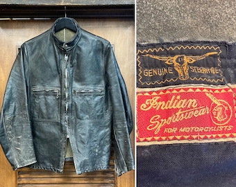 May include: A black leather motorcycle jacket with a zipper closure and two flap pockets. The jacket has a label that reads "Genuine Steerhide" and "Indian Sportswear for Motorcyclists".
