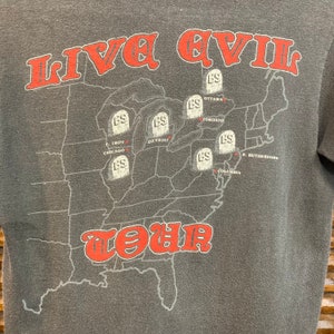 May include: A gray t-shirt with a map of the United States printed on the front. The map shows the locations of various cities where the band Live Evil toured. The text "LIVE EVIL TOUR" is printed in red letters on the map.