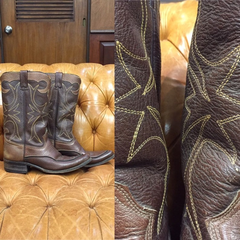 K&ouml;nnte beinhalten: Ein Paar braune Cowboy-Stiefel aus Leder mit spitzer Zehenpartie und einem gestickten Sternmuster in gelber Farbe.