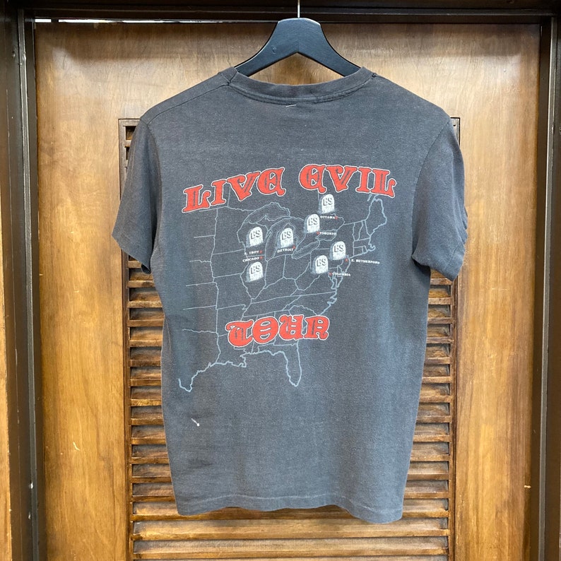 May include: A black t-shirt with a red graphic of a map of the United States. The map has the words "Live Evil Tour" and several tombstones with the letters "US" on them.