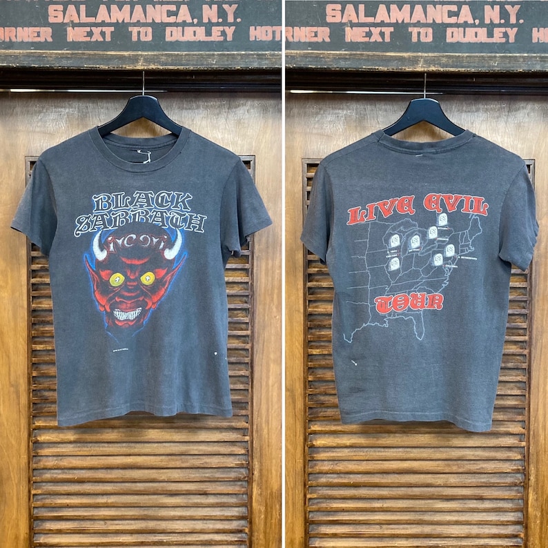 May include: Black Sabbath vintage concert t-shirt with a red devil graphic on the front and "Live Evil Tour" text on the back.