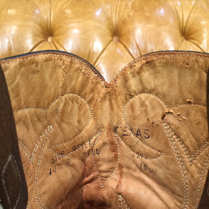 K&ouml;nnte beinhalten: Nahaufnahme des Innenraums eines braunen Leder-Cowboystickels. Der Stiefel ist mit "Texas" beschriftet und hat die Gr&ouml;&szlig;en- und Stilnummer "10 1/2 9744" auf der Innenseite.