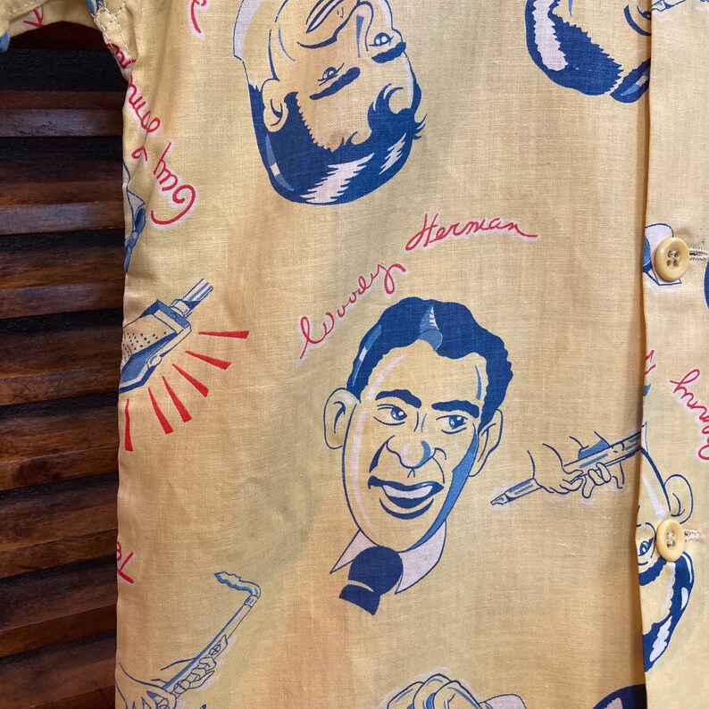 May include: A yellow button-up shirt with a blue and white print of musicians. The shirt has the text "Good Time" and "Lewy Herman" written on it.