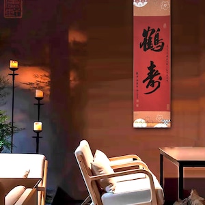 May include: A red and gold scroll with black calligraphy that reads "福寿" (meaning "good fortune and longevity") hanging on a wall in a room with two wooden chairs and a table.