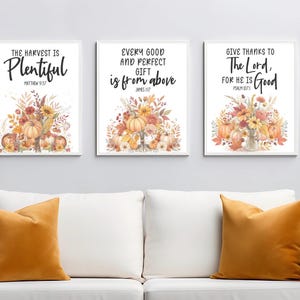 May include: Three framed art prints with fall-themed watercolor illustrations. Each print features a floral arrangement with pumpkins and text: "The Harvest is Plentiful," "Every Good and Perfect Gift is from Above," and "Give Thanks to The Lord, For He is Good."