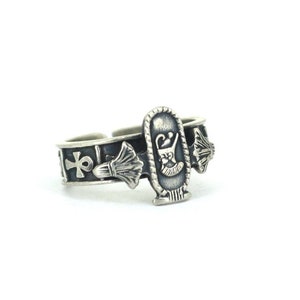 May include: Silver ring with an Egyptian ankh symbol and a scarab beetle design. The ring is adjustable and has a black oxidized finish.