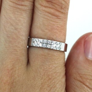 May include: A silver band ring with two rows of small, clear, square-shaped diamonds.
