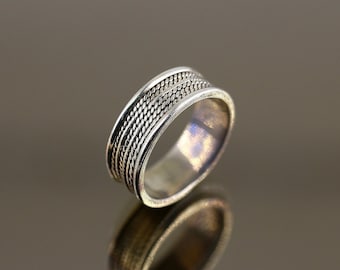 May include: A silver ring with a braided design on the band.