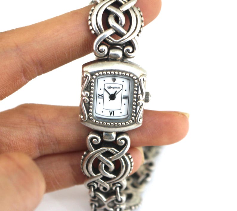 May include: A white ceramic mug with a black handle and the text "But First, Coffee" in a black, bold font. The mug is on a white surface. The mug is approximately 4 inches tall.