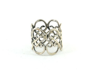 Puede incluir: Anillo para servilletas de plata con un diseño delicado e intrincado. El anillo está hecho de una sola pieza de metal y tiene forma circular.