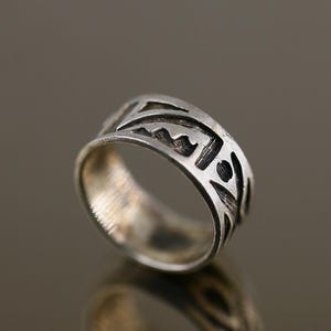 May include: A silver ring with a geometric design. The ring is made of sterling silver and has a black oxidized finish.