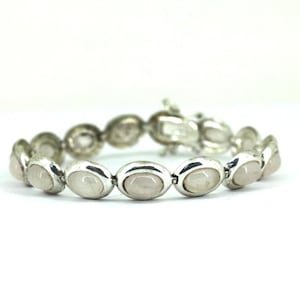 May include: A white ceramic mug with a black handle and the text "But First, Coffee" in a bold, black font. The mug is set against a blurred background, suggesting a cosy setting.