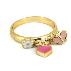 May include: A gold ring with three charms: a pink butterfly, a white flower, and a pink heart. The charms dangle from the ring.