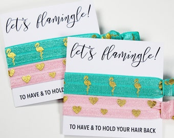 May include: Two sets of hair ties with a card that says "let's flamingle!"  The hair ties are pink and teal with gold glitter flamingo and heart designs. The card says "To have & to hold" and "To have & to hold your hair back".