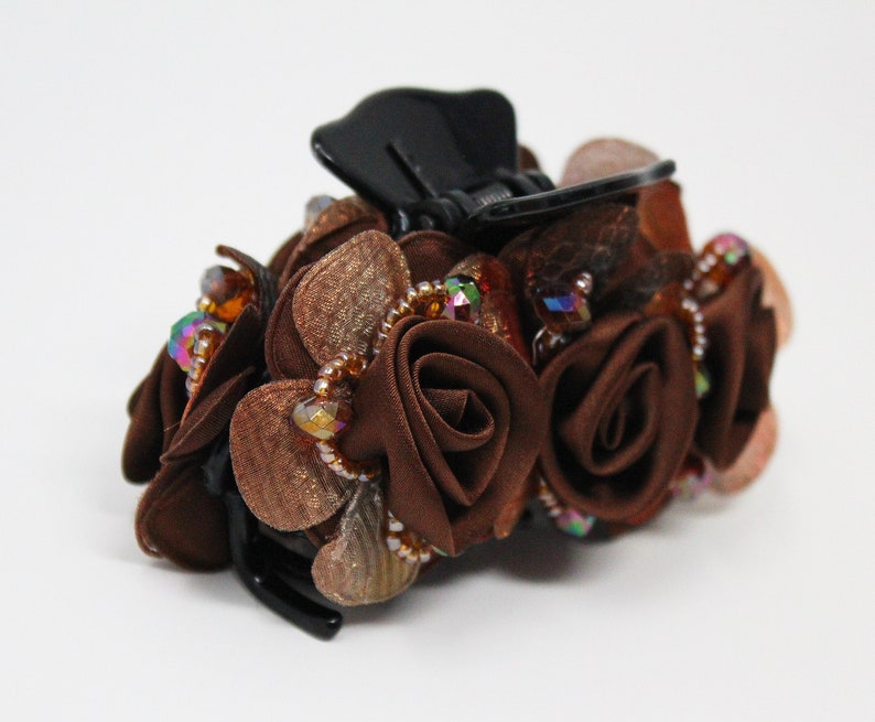 Może przedstawiać: Brązowa spinka do włos&oacute;w z czarną podstawą i skupiskiem brązowych r&oacute;ż z tkaniny ozdobionych tęczowymi koralikami.