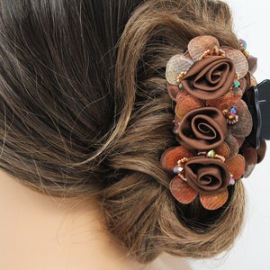 Może przedstawiać: Brązowa spinka do włos&oacute;w z trzema brązowymi kwiatami z tkaniny i brązowymi i złotymi koralikami.
