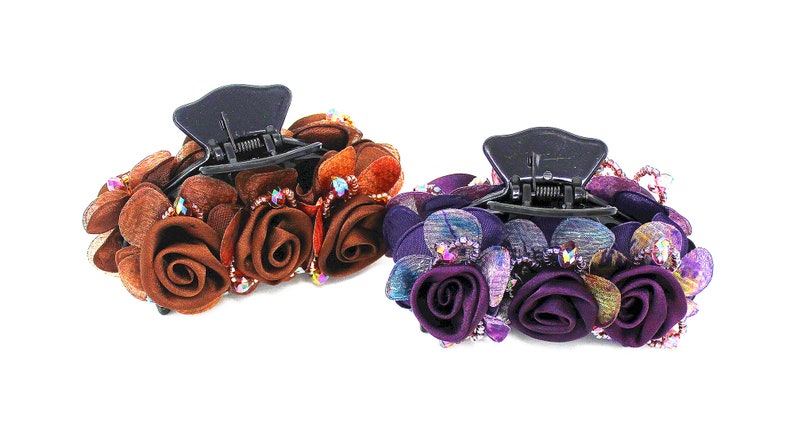 Może przedstawiać: Dwa spinki do włos&oacute;w z kwiatowym wzorem. Jedna spinka jest brązowa z brązowymi kwiatami, a druga jest fioletowa z fioletowymi kwiatami.