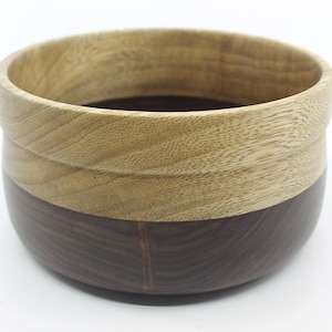 May include: A wooden bowl with a light brown top and a dark brown bottom. The bowl is made of two different types of wood.