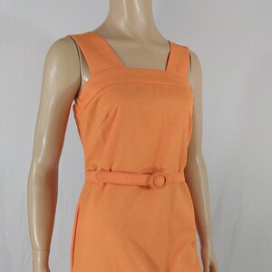 May include: A sleeveless orange dress with a square neckline and a belt with a round buckle.